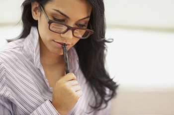 Close-up of a young woman holding a pen and thinking