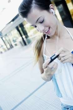 Young woman listening to an mp3 player and smiling