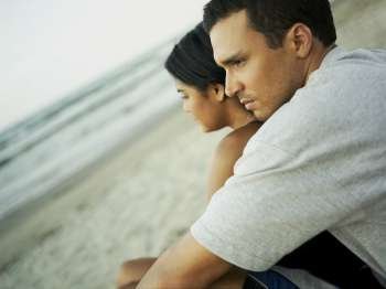 Side profile of a young couple sitting on the beach