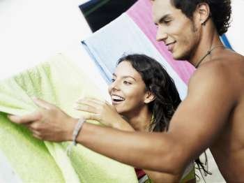 Close-up of a teenage girl and a young man drying a towel on a clothesline