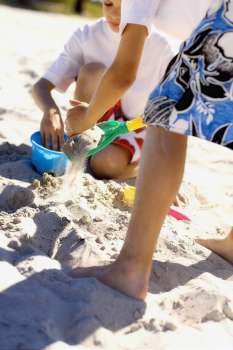 Two boys playing with sand pail and shovel on the beach