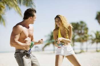 Young couple standing on the beach and pulling a rope