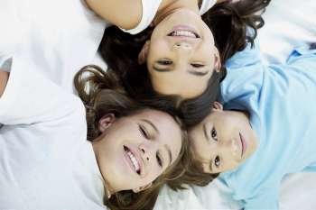 Close-up of a boy and his two sisters lying on the bed