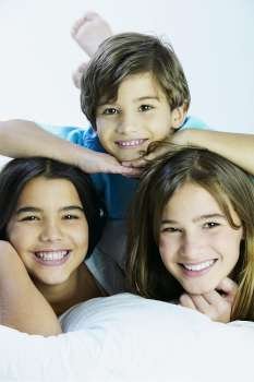 Portrait of a boy lying on the bed with his sisters