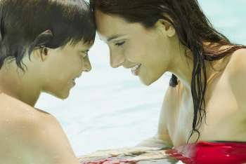 Side profile of a young woman with her son face to face in a swimming pool