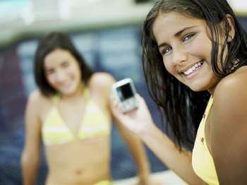 Portrait of a teenage girl holding a digital camera