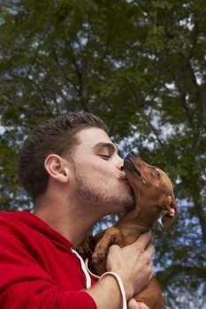 Close-up of a young man kissing his pet