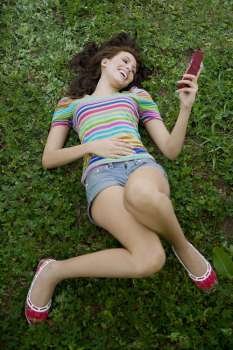 High angle view of a young woman holding a mobile phone and laughing