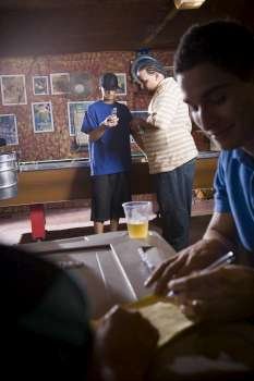 Young men looking at cellular phone while at billiard hall