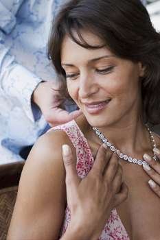 Man putting necklace on woman