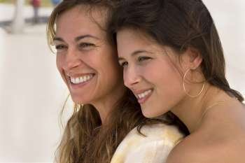 Two women sitting side by side at beach