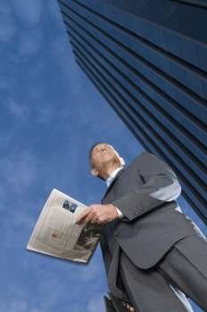 Low angle view of a businessman holding a newspaper