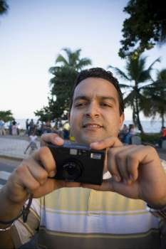 Close-up of a mid adult man holding a camera, Malecon, Santo Domingo, Dominican Republic