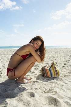 Young woman kneeling on beach