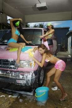 Three sexy young women washing a pink van in car wash