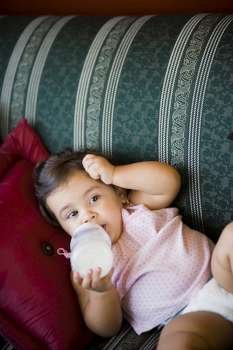 High angle view of a baby girl drinking milk with a baby bottle