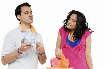 Young man holding a piggy bank and looking at a young woman