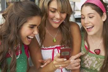 Teenage girl holding a mobile phone and smiling with her friends