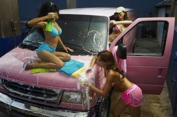 Three sexy young women washing a pink van in car wash