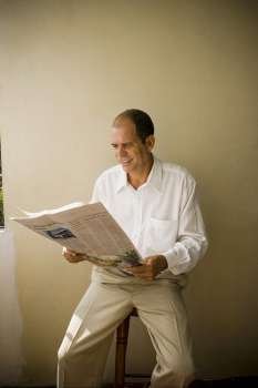 Mature man reading a newspaper and smiling