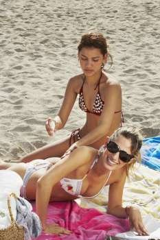 Young women putting on sun tan lotion
