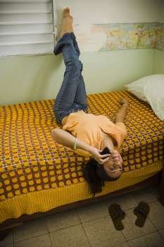 Teenage girl lying on the bed and talking on a mobile phone