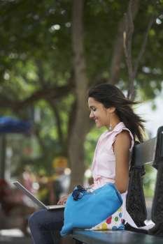 Side profile of a young woman sitting in a park and using a laptop, Old San Juan, San Juan, Puerto Rico