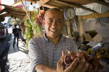 Portrait of a mature man holding a bunch of red grapes, Santo Domingo, Dominican Republic