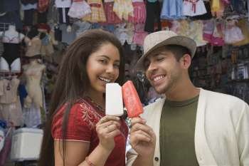 Portrait of a young couple holding ice creams and smiling