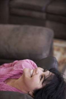 Side profile of a mature woman lying on a couch and smiling