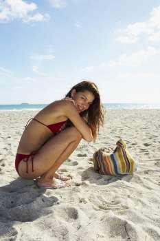 Young woman kneeling on beach