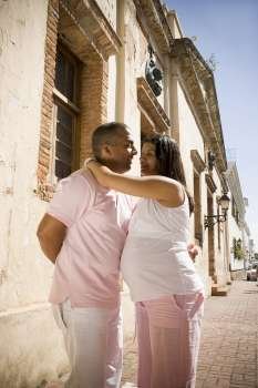 Side profile of a pregnant young woman embracing a mid adult man, Santo Domingo, Dominican Republic