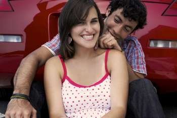 Close-up of a young couple sitting in front of a car