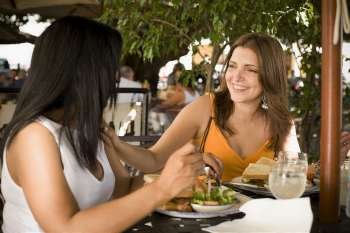 Mid adult woman and her friend sitting at a restaurant and smiling, Santo Domingo, Dominican Republic