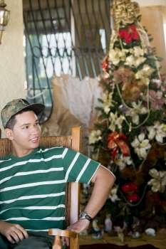 Young man sitting in front of a Christmas tree
