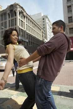 Side profile of a young couple reggaeton dancing on the road