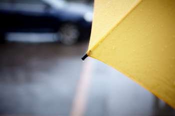 rainy walk with yellow umbrella, selective focus on part with drop