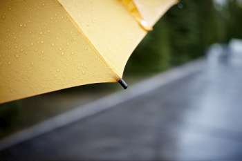 rainy walk with yellow umbrella, selective focus on nearest part