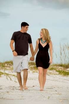 Cheerful young couple walking together on beach