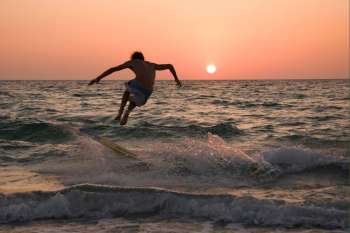 Young man surfing at sunset
