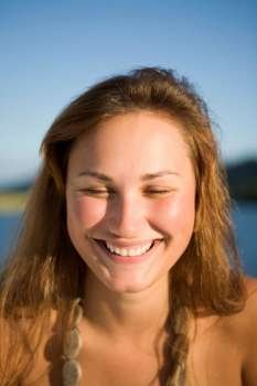 Young woman smiling, water in the background