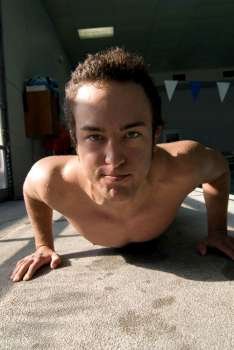 Serious bare chested man doing push-ups at poolside