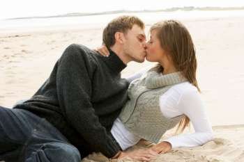 Portrait Of Romantic Young Couple Kissing On Beach