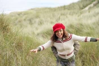 Teenage Girl Walking Through Sand Dunes Wearing Warm Clothing