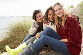 Three Teenage Girls Sitting In Sand Dunes Together