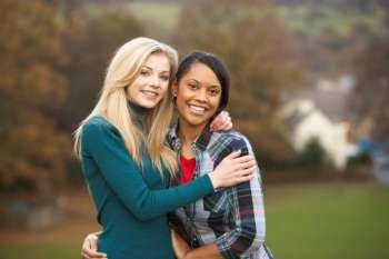 Two Female Teenage Friends On Walk In Autumn Landscape