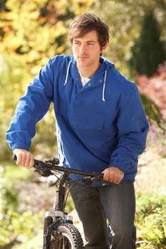 Portrait Of Young Man With Cycle In Autumn Park