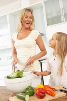Mother & Daughter Preparing Salad In Modern Kitchen