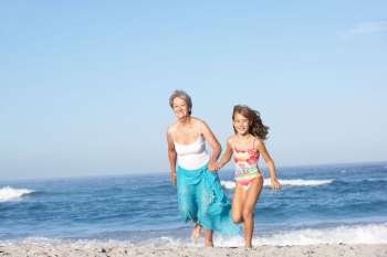 Grandmother Running With Granddaughter Along Sandy Beach