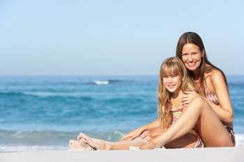 Mother And Daughter Relaxing Together On Beach Holiday